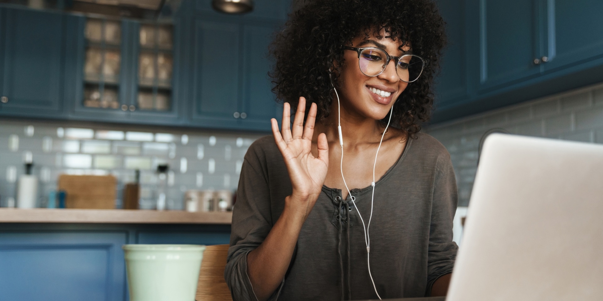 Woman smiling and waving during a video call, representing online therapy and telehealth counseling in Colorado