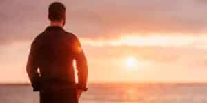 Man standing on the beach watching the sunset