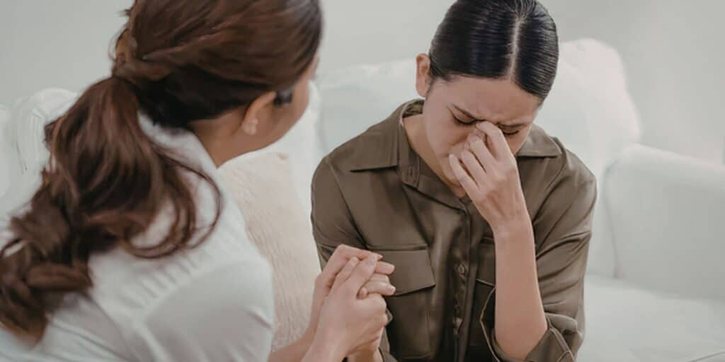 Woman comforting a crying friend by holding her hands
