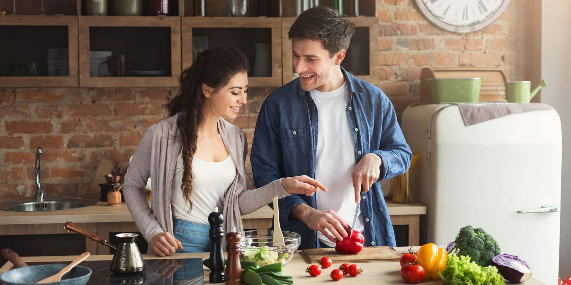 Happy couple cooking a healthy meal together in their kitchen